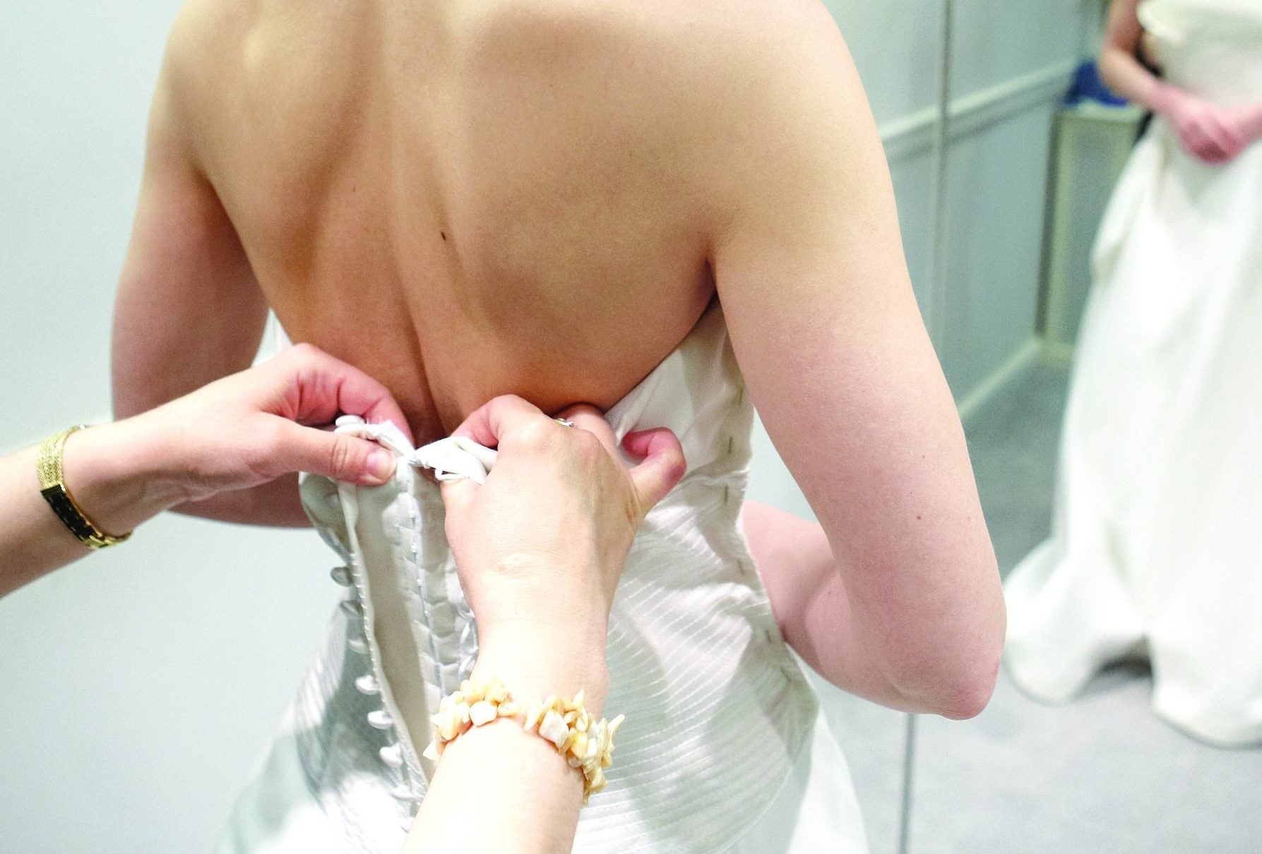 pinning dress onto bride