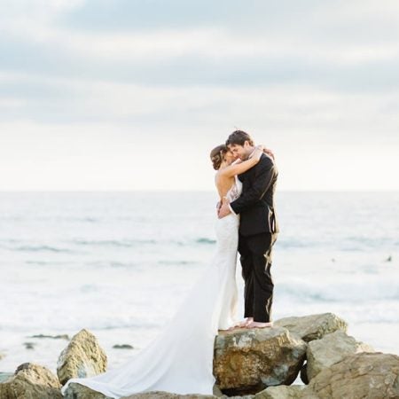 kristen and chase hugging on rocks by the beach